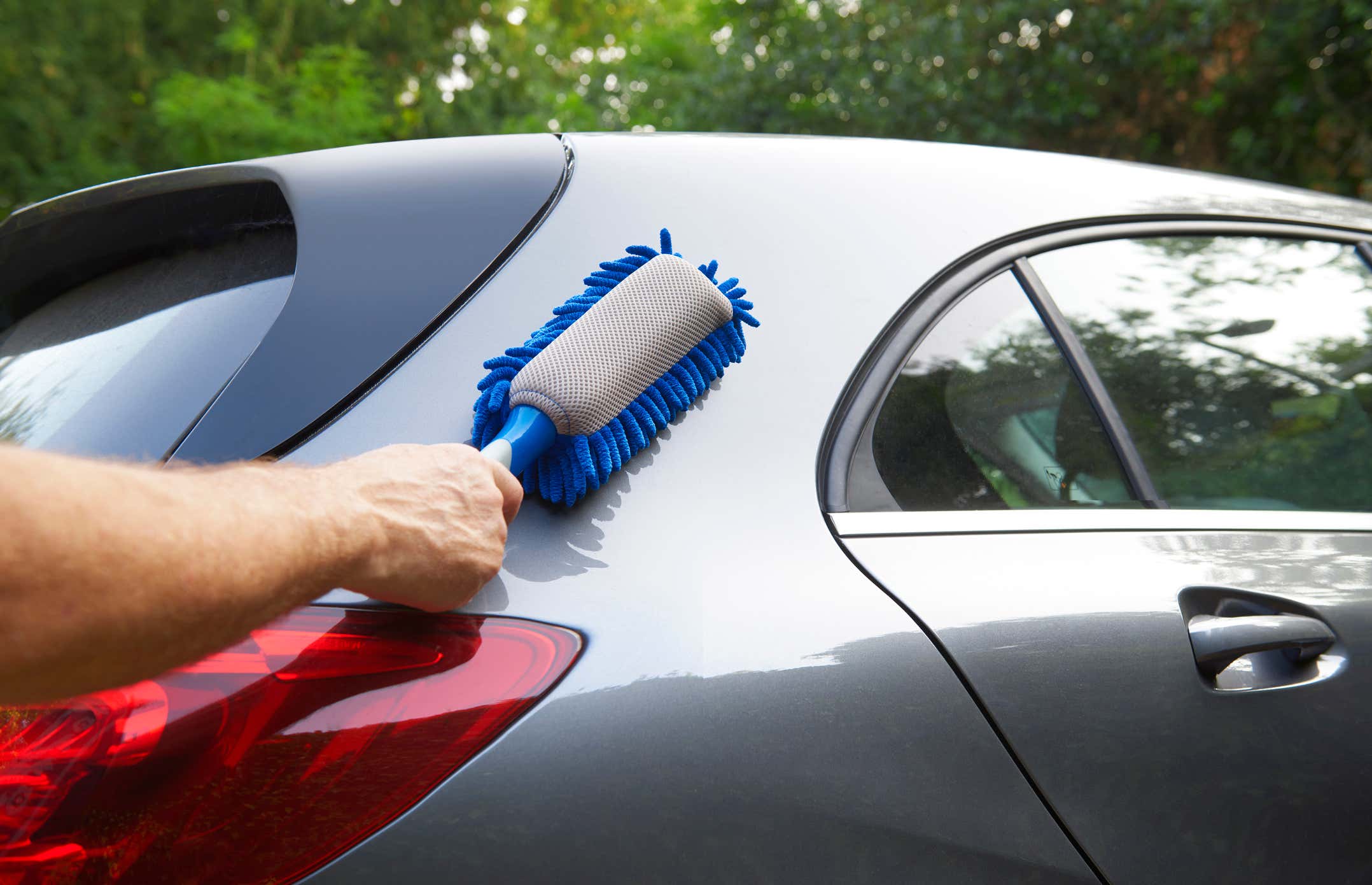 Outside of car being cleaned by hand with blue duster 用蓝色掸子手动清洁车外
