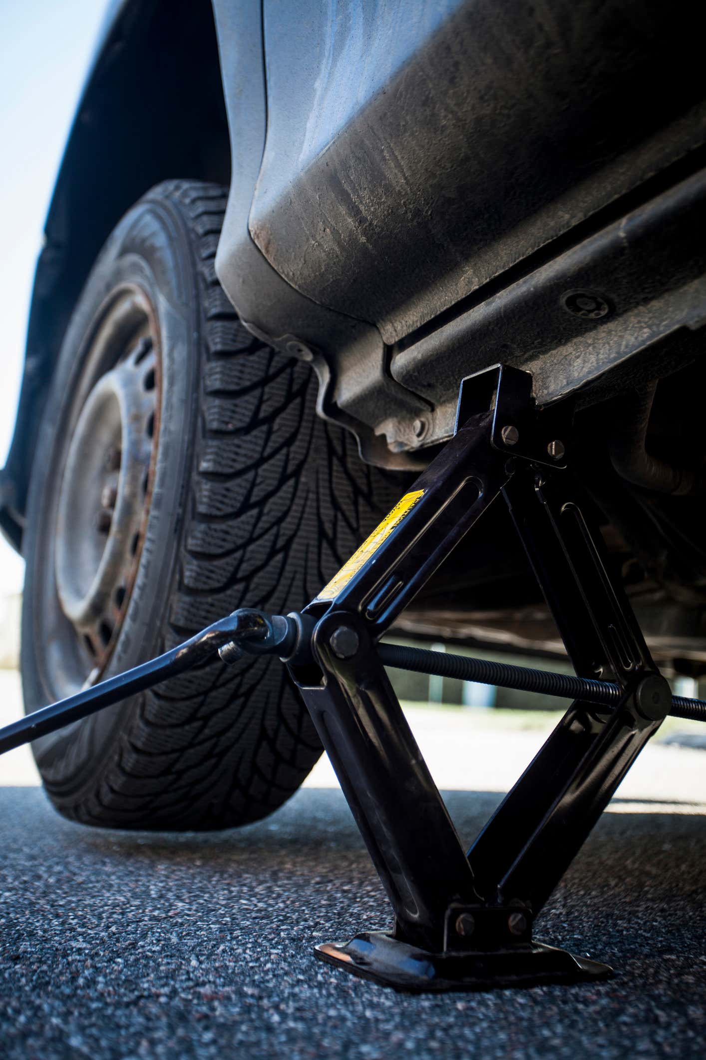 Shot of car jack and tire from underneath vehicle 汽车千斤顶和车胎被击中