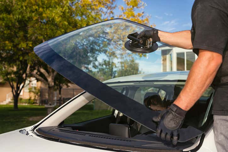 A man replacing a windshield in a car. 一名男子正在更换汽车的挡风玻璃。