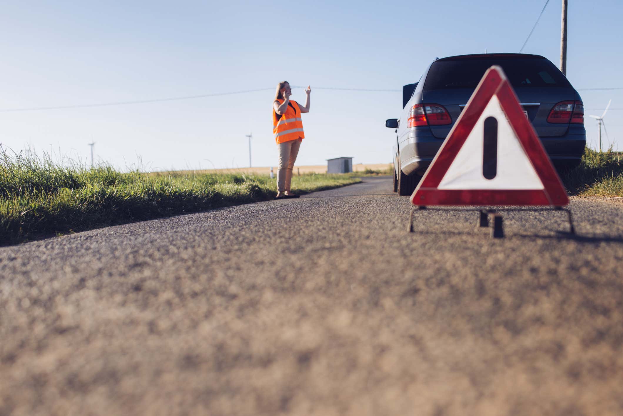 A woman with a broken down car on the side of the road. 一名妇女在路的一边有一个破碎的汽车。