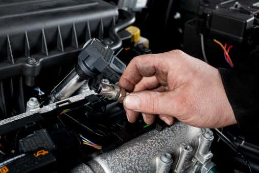 A mechanic working on a vehicle’s spark plugs. 修理汽车火花塞的技工