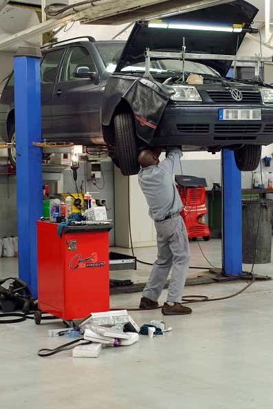 A man repairing a VW on a lift at a car dealership 修理在电梯的一个人在汽车经销商的电梯