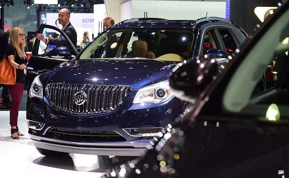 People inspect a Buick Enclave on display at the LA Auto Show 人们在洛杉矶车展上参观展出的别克飞地