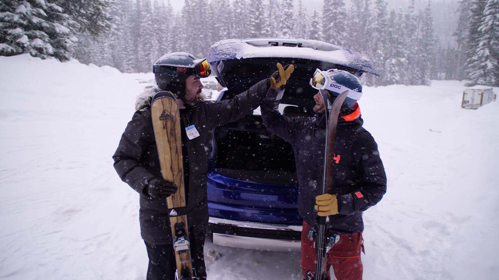 The author hi-fives his friend in front of a Rolls-Royce Cullinan SUV. 作者在一辆劳斯莱斯库里南SUV前和他的朋友击掌。