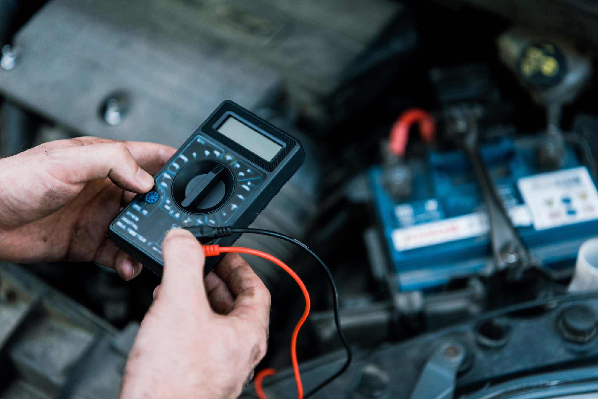 A mechanic testing a battery with a multimeter. 用万用表测试电池的机械师。