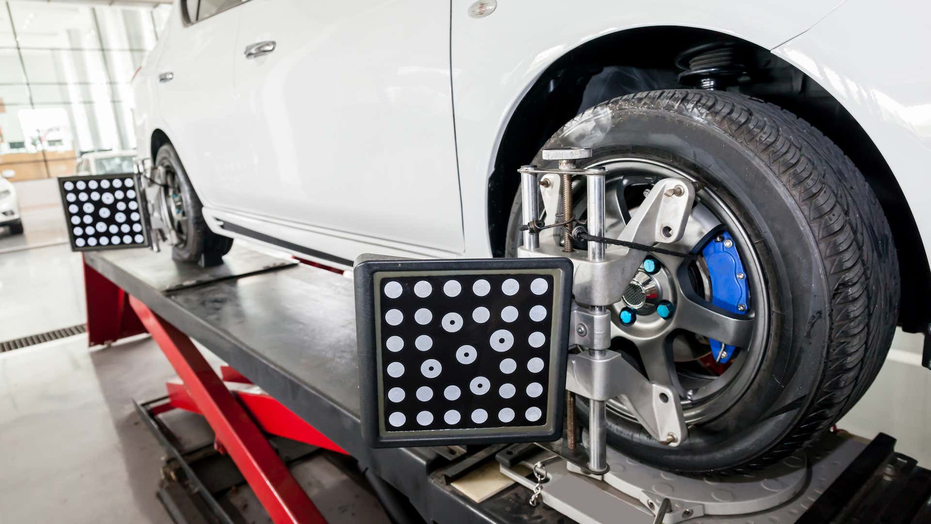 A car sits on a lift with wheel alignment tools attached. 一辆汽车坐在电梯与车轮对准工具连接。
