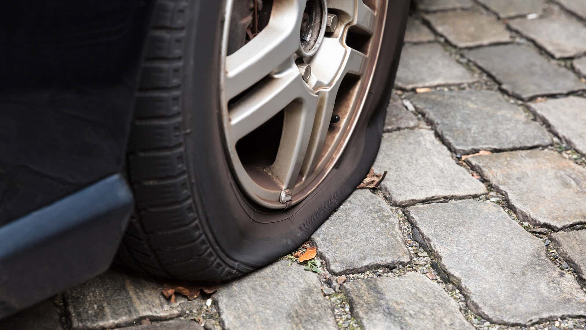 A flat tire sits on brick pavers. 一个扁平的轮胎坐在砖摊铺机上。