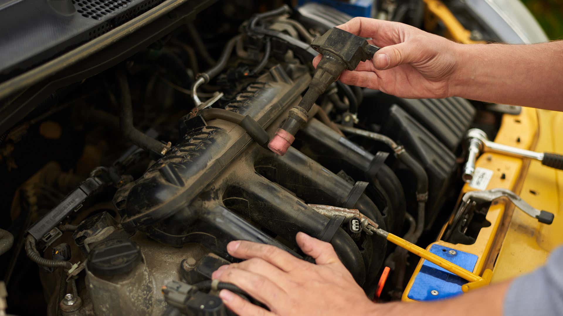 A man checks his ignition coils and spark plugs. 一名男子检查他的点火线圈和火花塞。