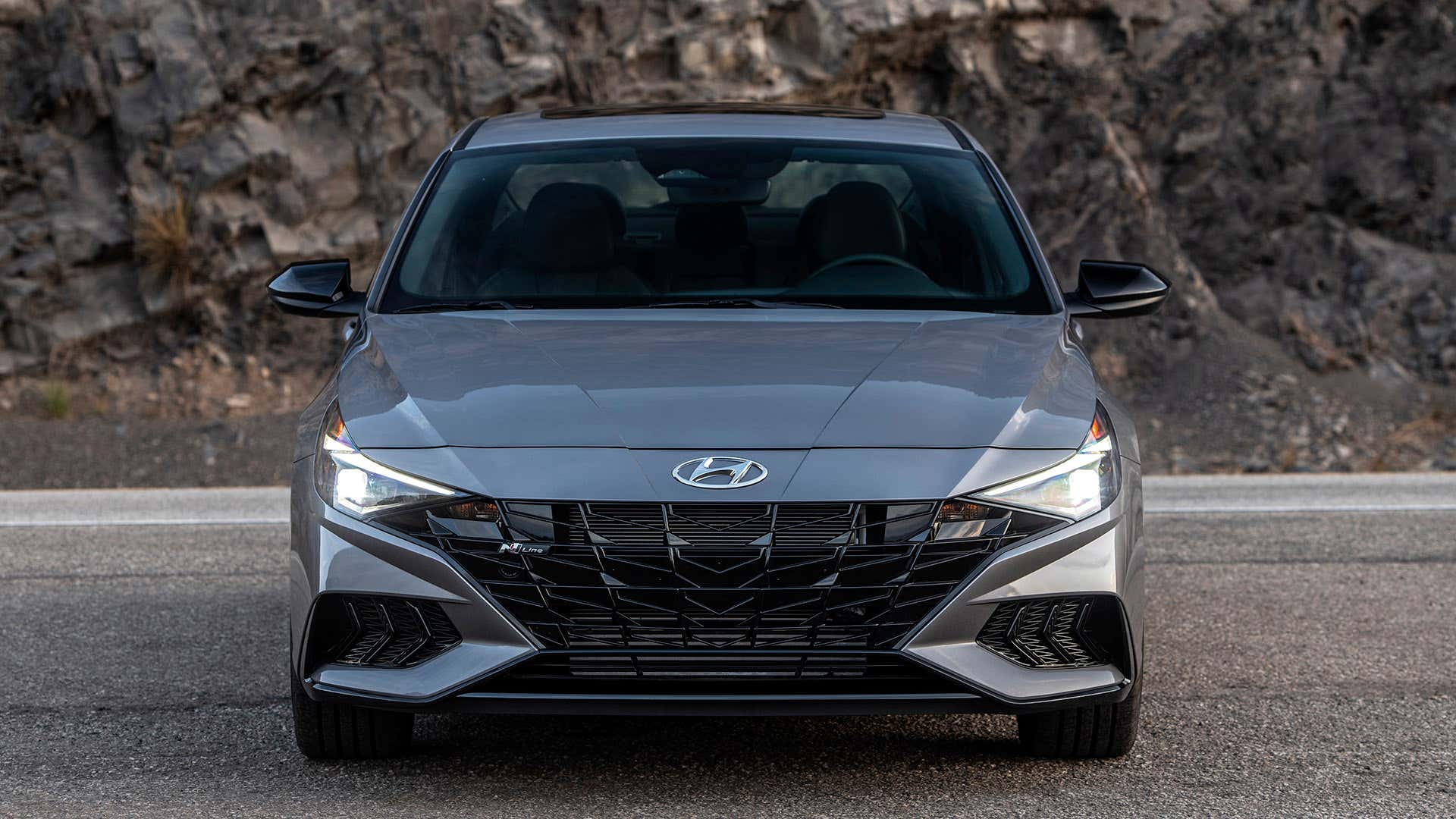 A gray Hyundai Elantra sits on a canyon road facing the camera. 一辆灰色的现代伊兰特坐在峡谷公路上,面对着摄像机。