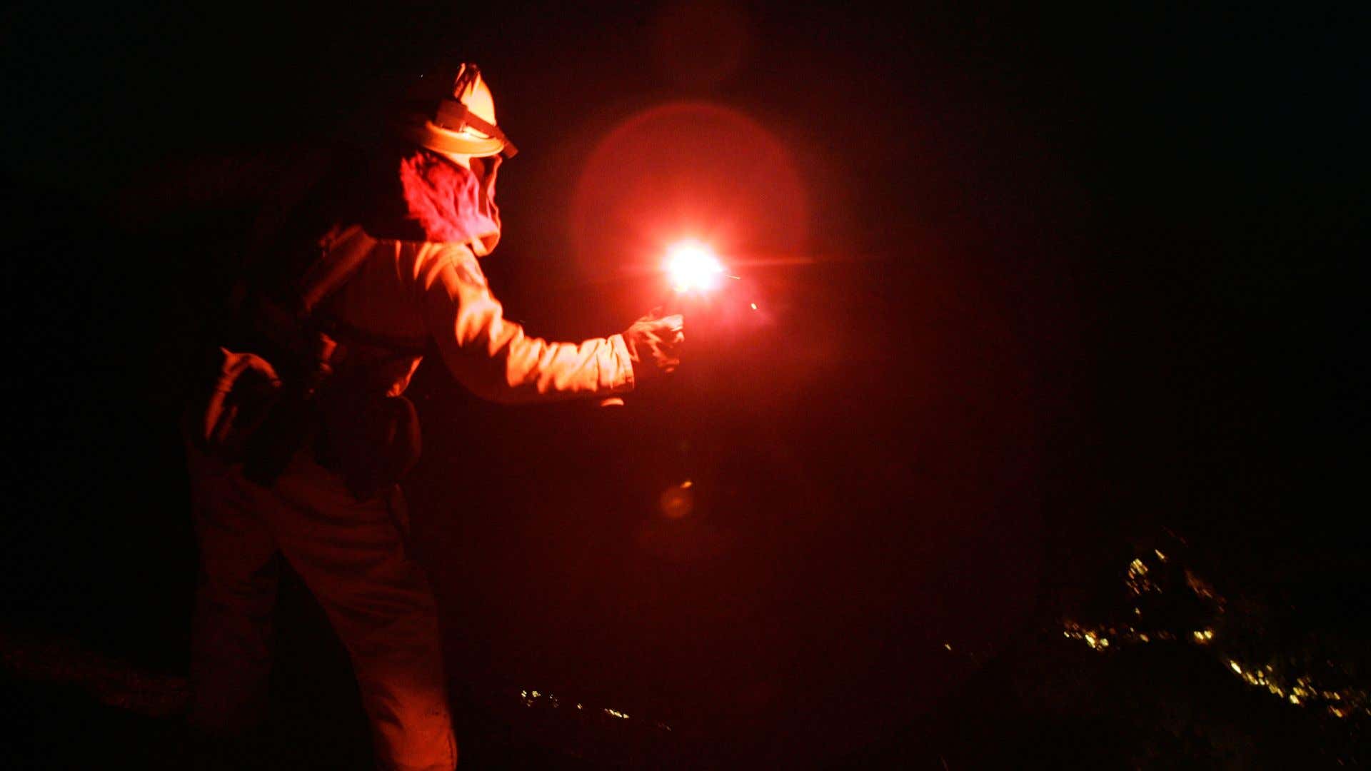 A firefighter throwing a flare. 一名消防员投掷火炬。