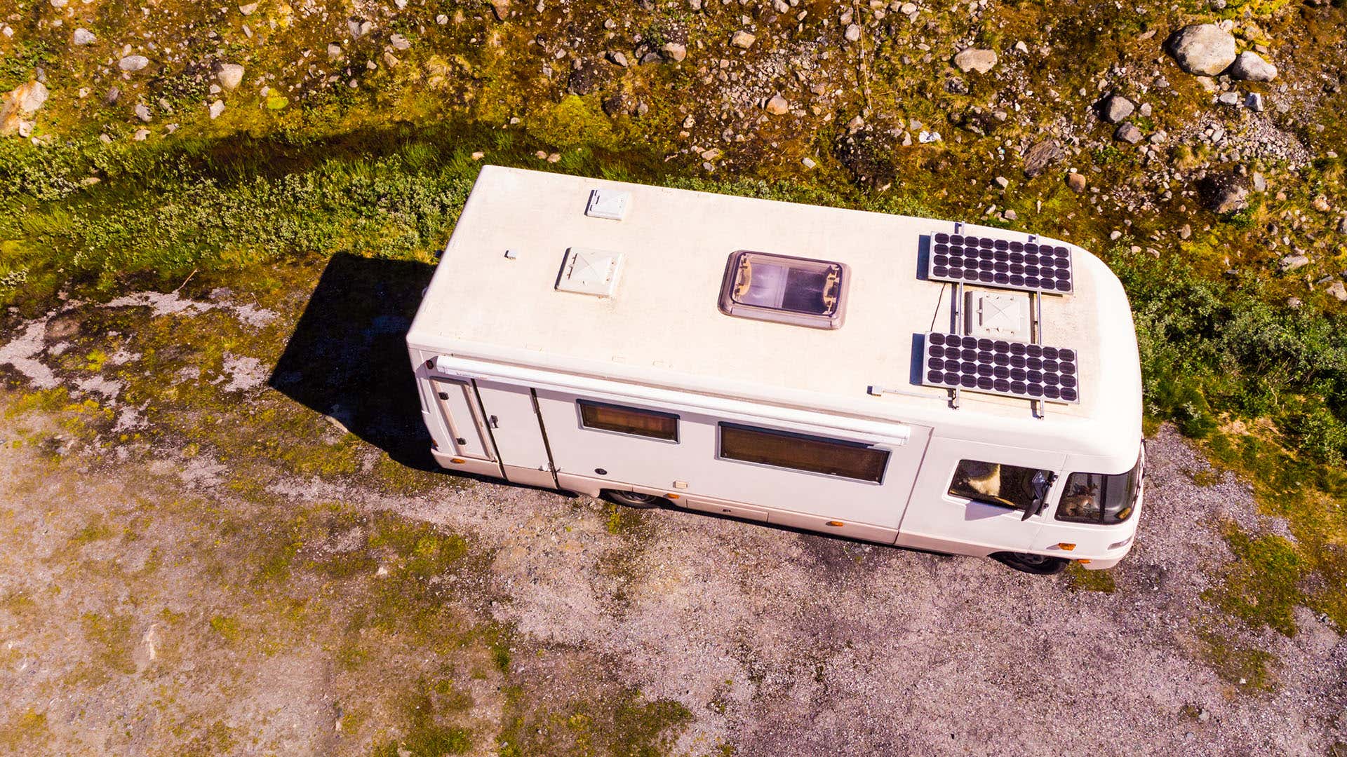 An RV with solar panels sits parked in nature. 一辆装有太阳能电池板的房车停在大自然中。