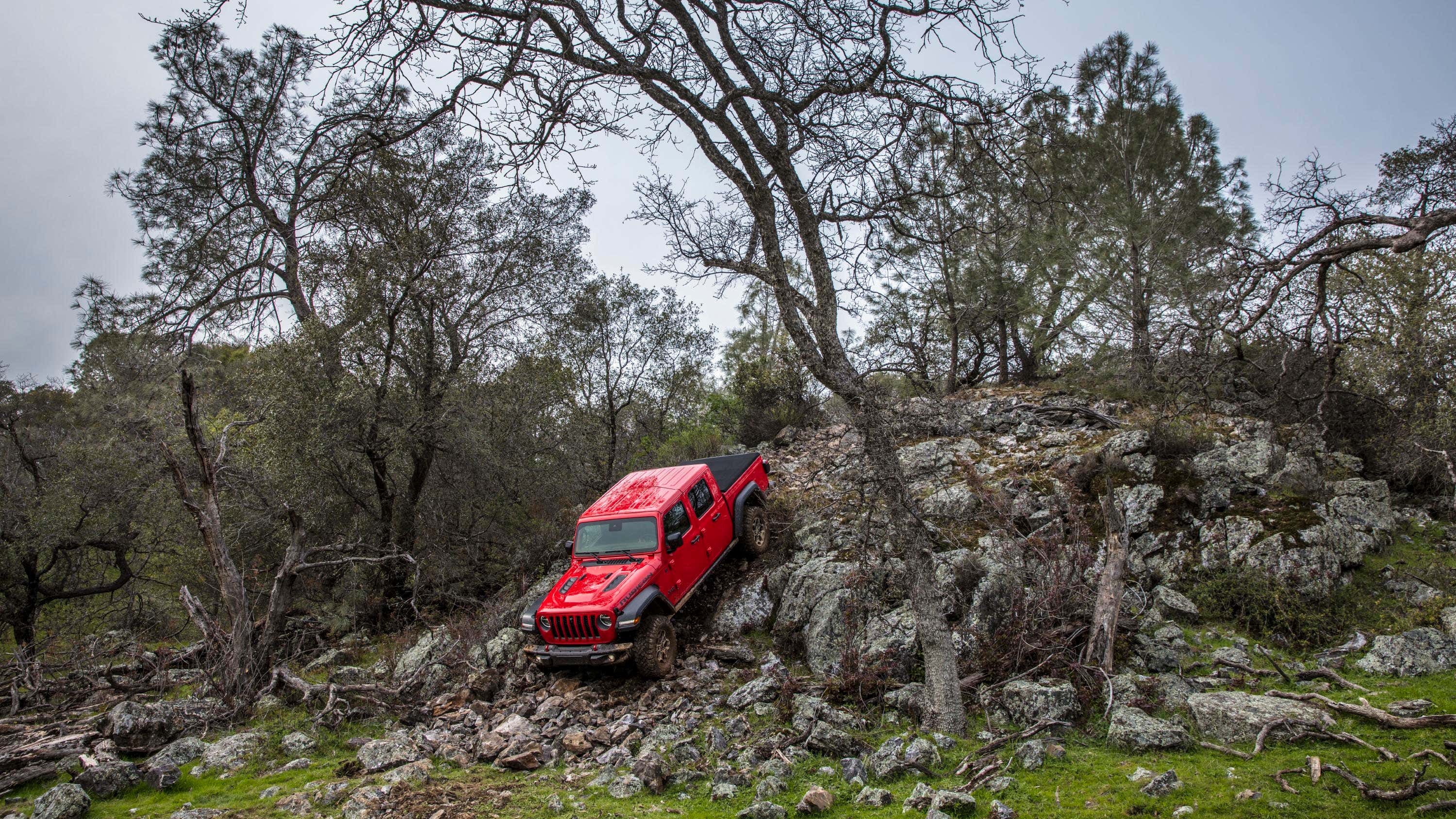 A red Jeep Gladiator crawls down a rocky mountain. 一个红色的吉普歌单斗士爬行落下落矶山脉。