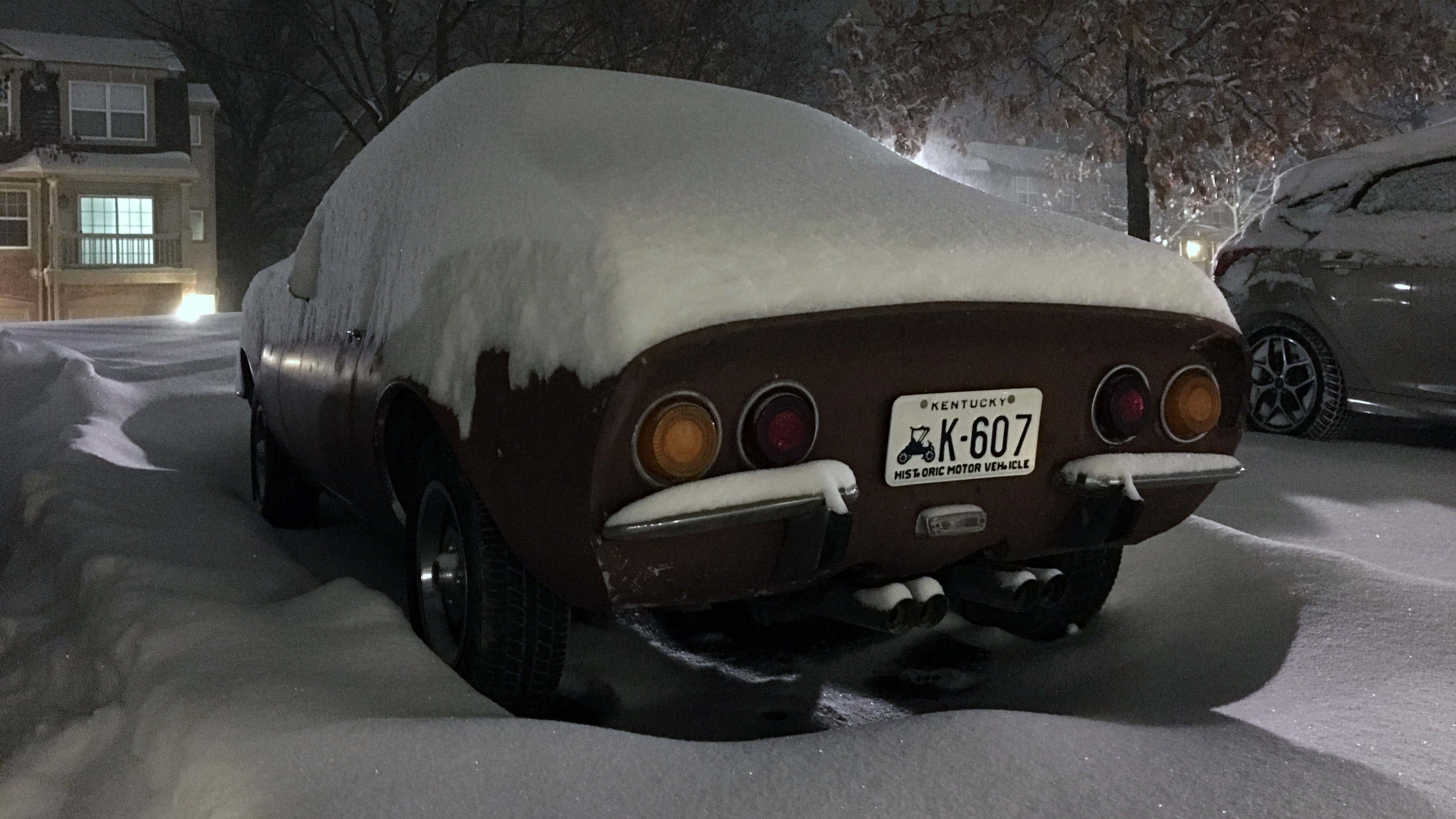 An Opel GT sits in a parking lot buried in snow. 一辆欧宝GT停在被雪埋着的停车场里。
