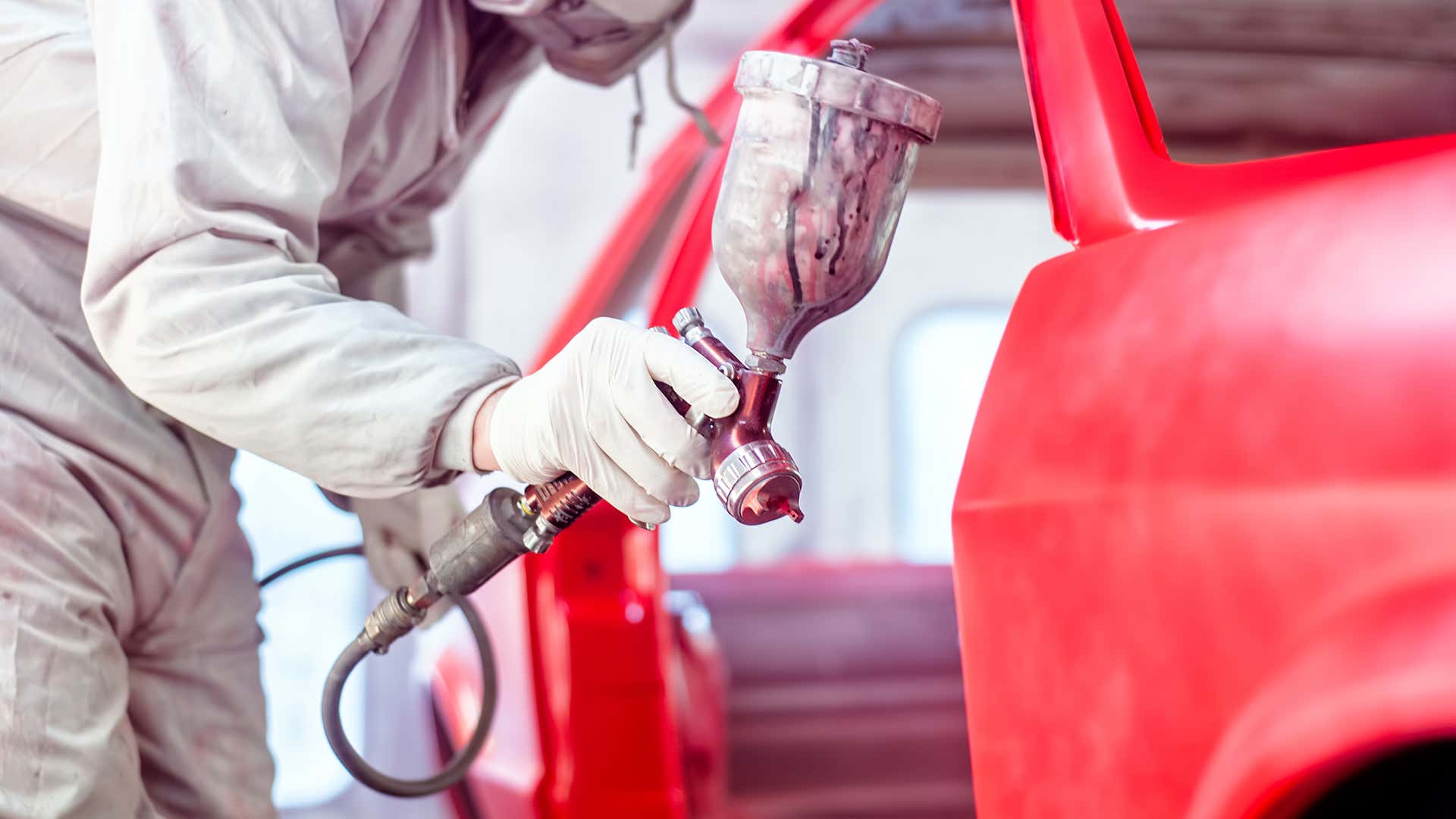 A person uses a pneumatic paint sprayer to paint a car. 一个人使用气动涂料喷雾器涂上汽车。