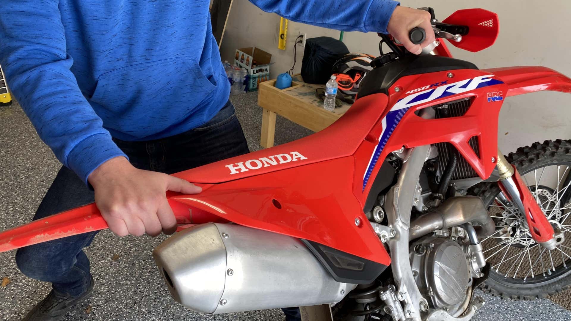 The author's hands on the handlebar and rear fender of the CRF450RX. 作者的手放在CRF450RX的把手和后挡泥板上。