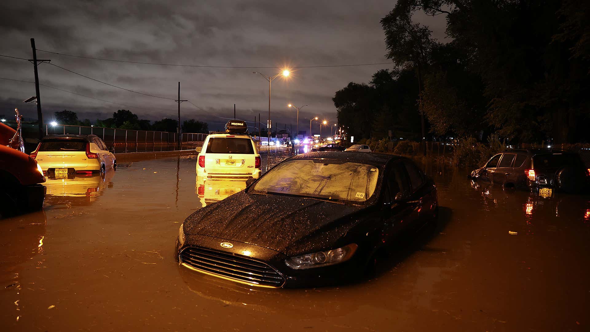 A Volv XC40, a Ford Fusion, a Honda Pilot, and a Toyota Rav4 sit in flood waters at night. 一辆沃尔沃XC40、一辆福特Fusion、一辆本田Pilot和一辆丰田Rav4在晚上被洪水淹没。