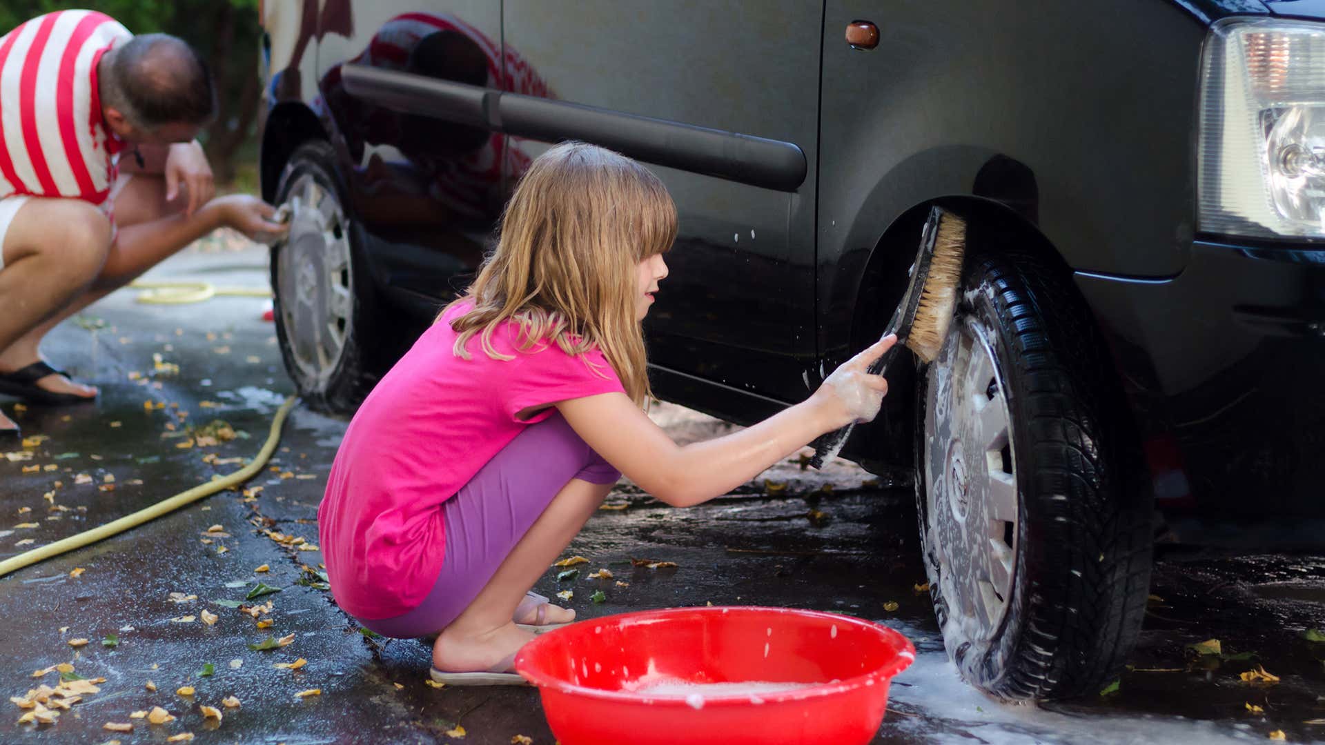 用硬毛刷清洗汽车轮胎。